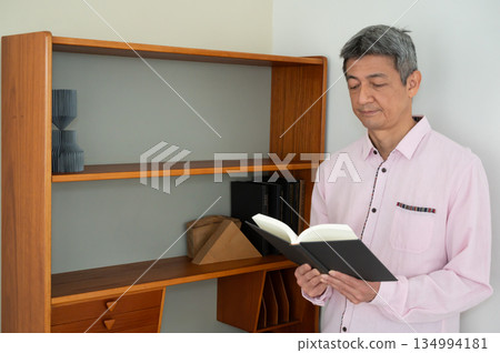 一個男人在書架前看書。 134994181