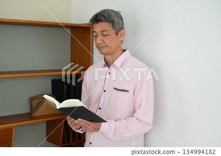 一個男人在書架前看書。 134994182