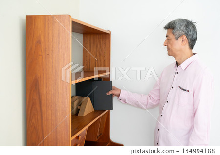 A man picking up a book from a bookshelf A man picking up a book from a bookshelf 134994188
