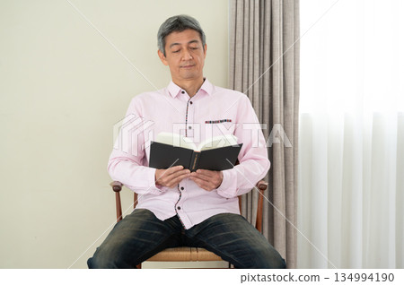Man sitting on a chair and reading a book Man sitting on a chair and reading a book 134994190