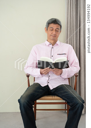Man sitting on a chair and reading a book Man sitting on a chair and reading a book 134994192