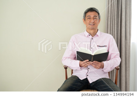 Man sitting on a chair and reading a book 134994194