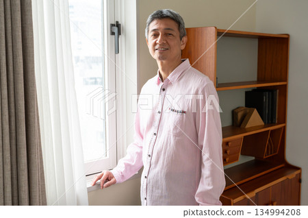 A man standing by the window A man standing by the window 134994208