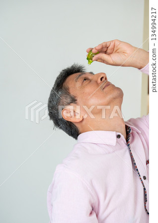 一名男子坐在椅子上滴眼藥水 134994217