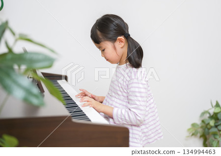 Child practicing on an electronic piano Child practicing on an electronic piano 134994463