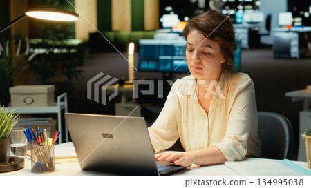 Discouraged woman creating plans and documenting objectives to share with executives during next morning meeting. Employee drained and in a mental haze doing overtime, pushing limits. Camera B. Discouraged woman creating plans and documenting objectives to share with executives during next morning meeting. Employee drained and in a mental haze doing overtime, pushing limits. Camera B. 134995038