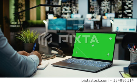 African american man working with green screen on laptop in corporate workspace, checking online data and insights in strategy room. Male general manager setting the business agenda. 134995114