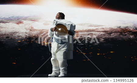 Astronaut removing helmet to look at planet during scientific mission, mesmerized by beauty. Spaceship crew member in high tech spacesuit proud after reaching planetary outer space planet, camera A Astronaut removing helmet to look at planet during scientific mission, mesmerized by beauty. Spaceship crew member in high tech spacesuit proud after reaching planetary outer space planet, camera A 134995126