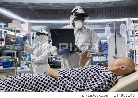 Scientist in protective gear works in biohazard zone to treat a contagious patient, analyzing infection data to advance immunology and epidemic prevention in biotechnology research. 134995148