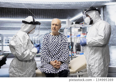 Virology professionals with gloves and mask treating infected old patient, performing diagnostics and analyzing infection symptoms. Vaccine formulas for prevention to avoid a global disaster. Virology professionals with gloves and mask treating infected old patient, performing diagnostics and analyzing infection symptoms. Vaccine formulas for prevention to avoid a global disaster. 134995169