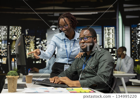 African american team of employees working late on goal setting, studying data insights and performance metrics. Colleagues creating reports for business administration, strategy room. 134995220