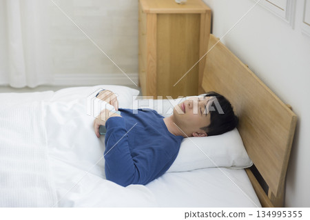年輕人在床上觀看智能手機 134995355