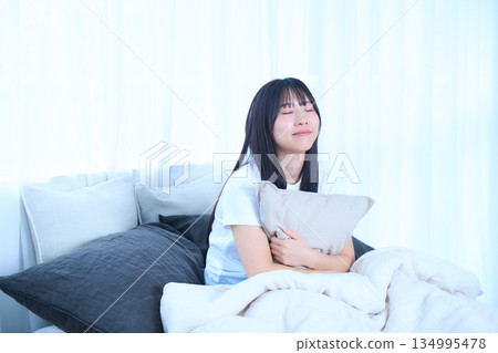 年輕女子抱著枕頭躺在床上 134995478