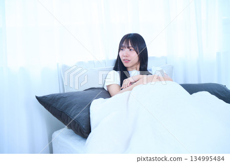 年輕女子抱著枕頭躺在床上 134995484