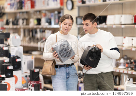 Young couple chooses portable heater at hypermarket 134997599