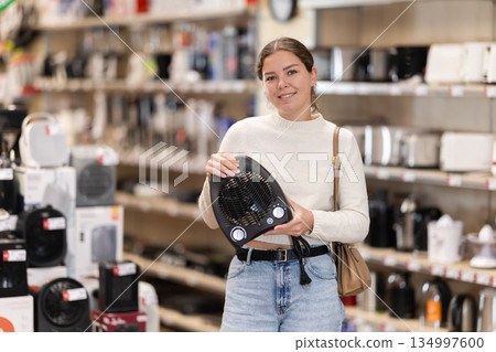 Young woman chooses portable heater in appliance store Young woman chooses portable heater in appliance store 134997600