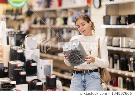 Young woman chooses portable heater in appliance store Young woman chooses portable heater in appliance store 134997606