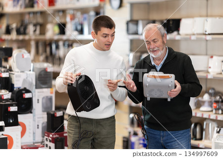 Eldery and young man choose portable heater Eldery and young man choose portable heater 134997609
