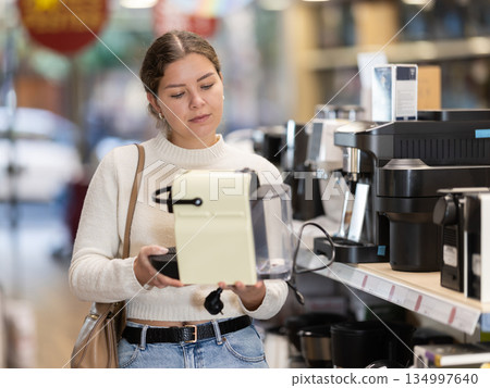 Young woman chooses coffee machine in appliance store Young woman chooses coffee machine in appliance store 134997640