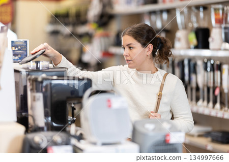 Young woman standing near counter in store with appliances 134997666
