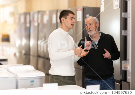 Elderly and young man choosing refrigerator Elderly and young man choosing refrigerator 134997680