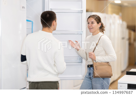 Young couple chooses modern fridge at hypermarket Young couple chooses modern fridge at hypermarket 134997687
