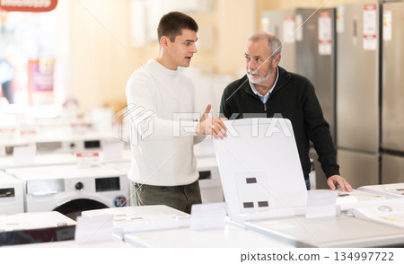 Elderly and young man choose washing machine or dishwasher Elderly and young man choose washing machine or dishwasher 134997722