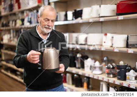 Elderly man chooses kettle in appliance store Elderly man chooses kettle in appliance store 134997814