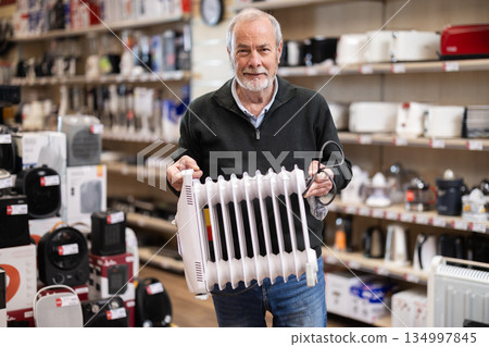Elderly man chooses oil heater in appliance store Elderly man chooses oil heater in appliance store 134997845