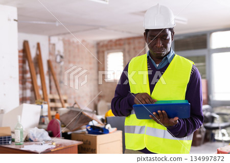 Man construction worker with laptop inside apartment 134997872