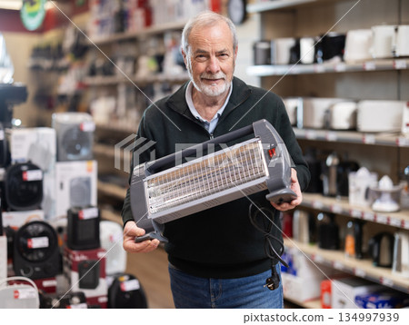 Elderly man choosing a portable heater Elderly man choosing a portable heater 134997939