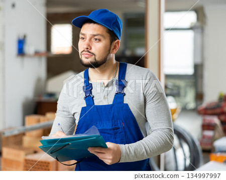 Builder making notes on indoor construction site 134997997