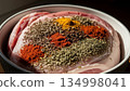 Raw pork meat marinated with colorful spices fennel seeds turmeric paprika herbs in white ceramic bowl preparation 134998041