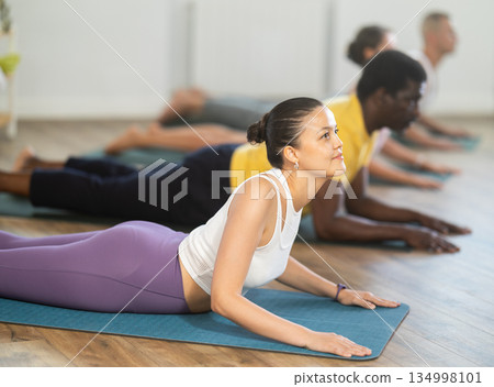Asian woman performing Sphinx Pose during group yoga training 134998101