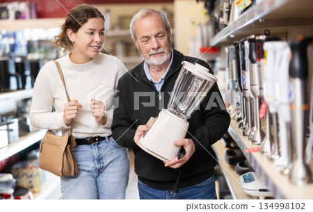 Young woman with elderly man choosing blender in store Young woman with elderly man choosing blender in store 134998102