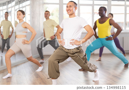 Young Asian man doing leg exercises in training hall Young Asian man doing leg exercises in training hall 134998115