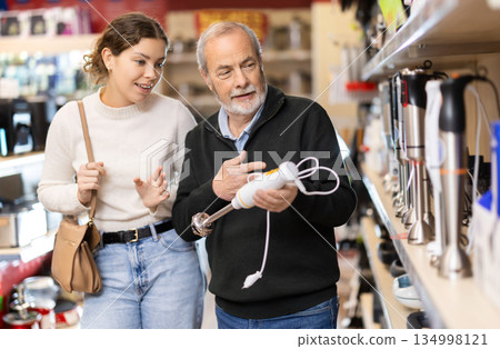 Young woman with elderly man choosing blender in store Young woman with elderly man choosing blender in store 134998121