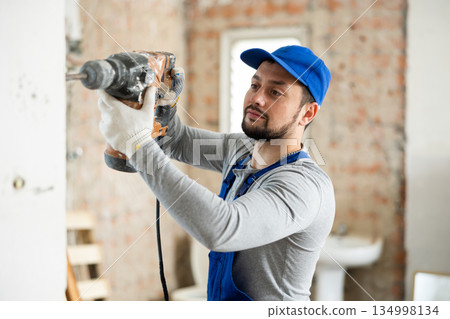 Confident builder posing on indoor construction site 134998134