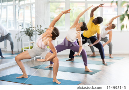 Girl stretching in Goddess Pose with side bend in yoga class Girl stretching in Goddess Pose with side bend in yoga class 134998143