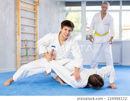 Cheerful guy practicing armlock in training bout during martial arts course 134998152
