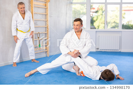 Men train to throw on the mat under the guidance of judo coach Men train to throw on the mat under the guidance of judo coach 134998170