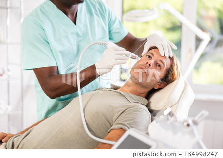 doctor meticulously performs cosmetic procedure doctor meticulously performs cosmetic procedure 134998247