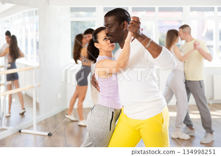 Middle-aged man and woman practicing tango dance in pair in training hall 134998251