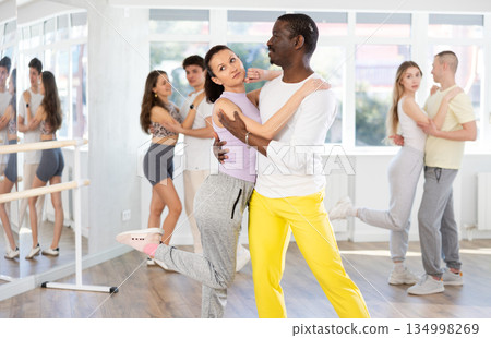 Middle-aged man and woman practicing salsa dance in pair in training hall Middle-aged man and woman practicing salsa dance in pair in training hall 134998269