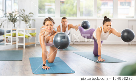 Men and woman diligently perform set of exercises with fitball during training session 134998283