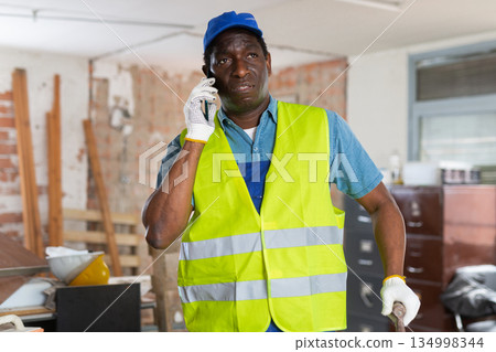 African american contractor with papers talking on phone at construction site 134998344