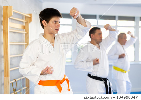 Fighting stance of men of different ages during group karate training. Guy trains punches 134998347