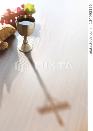 The bread and wine of the Eucharist and the inverted shadow of the cross symbolizing the suffering of Jesus Christ 134998356