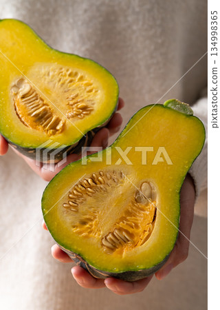 Half green butternut squash pumpkin holding by woman hand Half green butternut squash pumpkin holding by woman hand 134998365