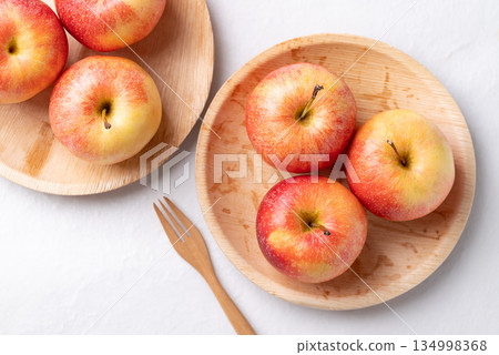 Red apple fruit (Gala apple) in natural plate with wooden fork on white background Red apple fruit (Gala apple) in natural plate with wooden fork on white background 134998368